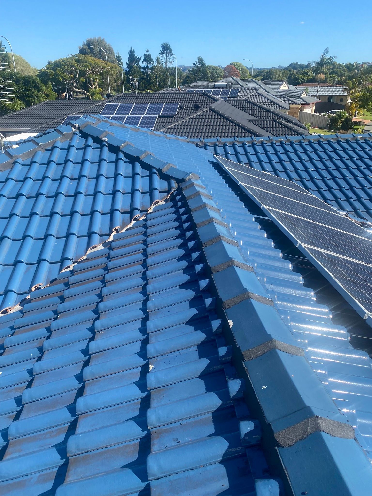 Blue Tiled Roof With Solar Panels. Sunny Day — Killiby & Co Roofing Pty Ltd in Byron Bay, NSW