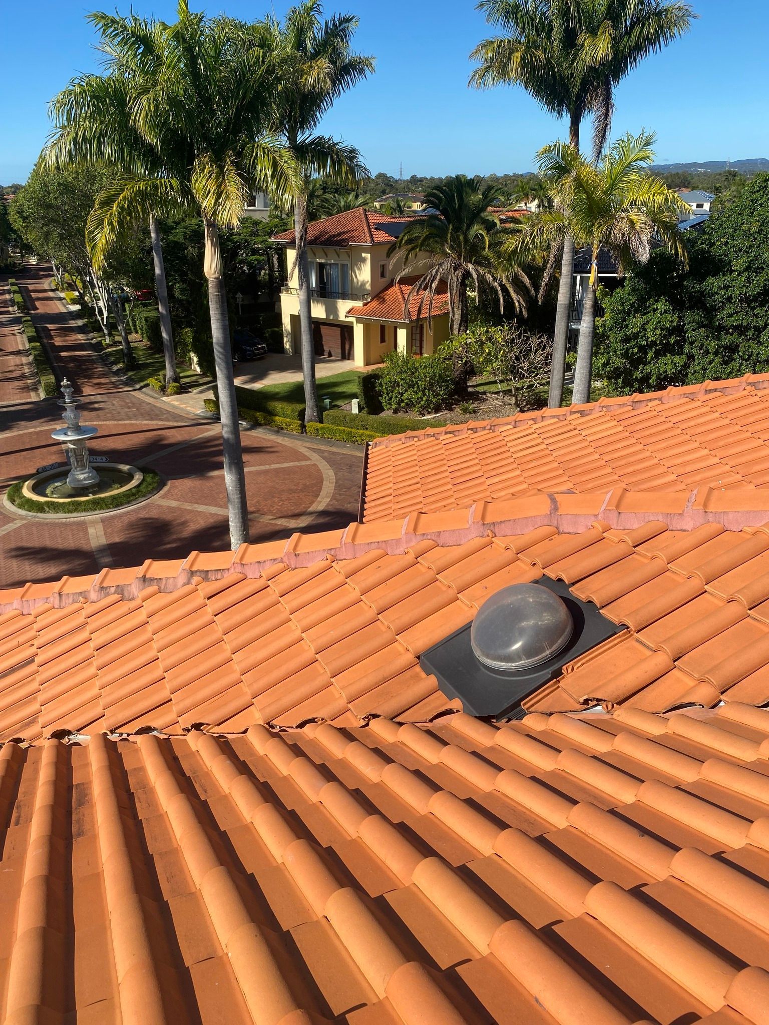Orange Tile Roof With a Vent Cap, View of a Building and Trees — Killiby & Co Roofing Pty Ltd in Currumbin, QLD