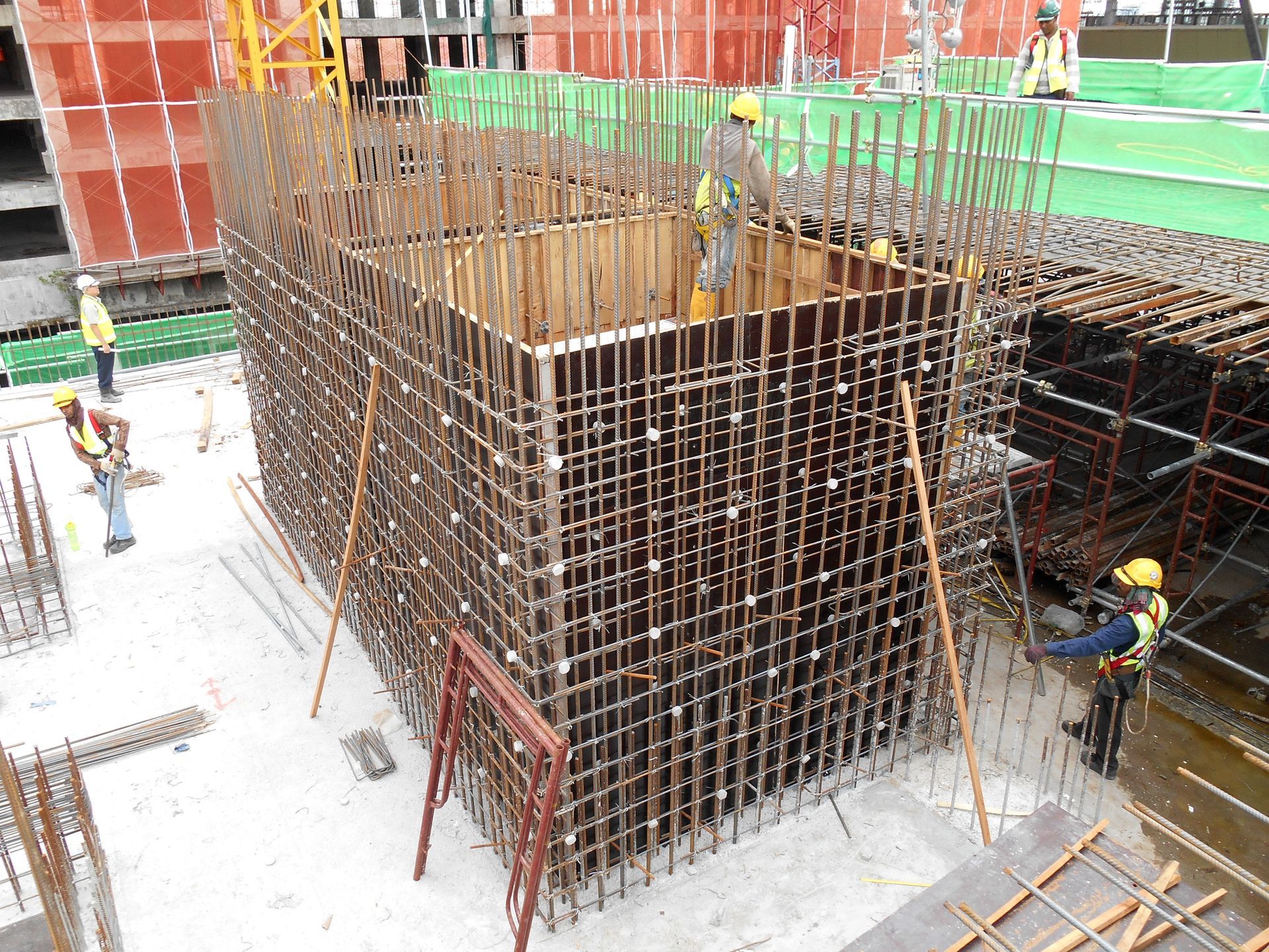 Construction workers fabricating a steel reinforcement bar at a construction site. Construction workers fabricating a steel reinforcement bar at a construction site.