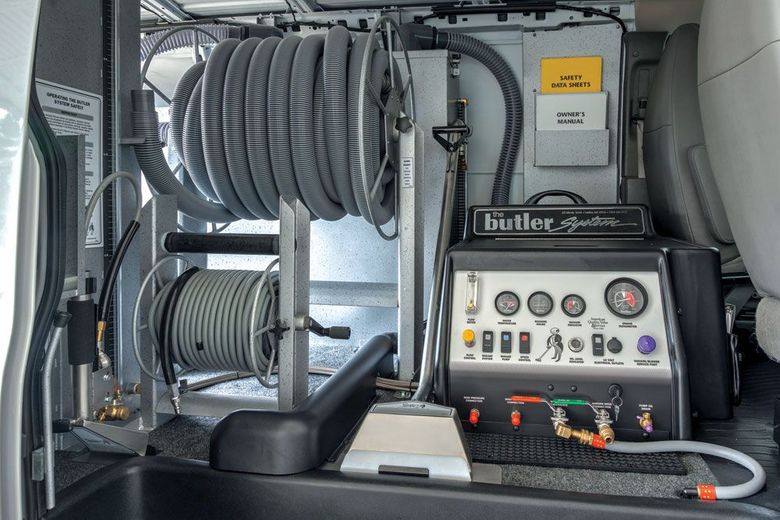 Interior of a van, showing carpet cleaning equipment and hose reels.