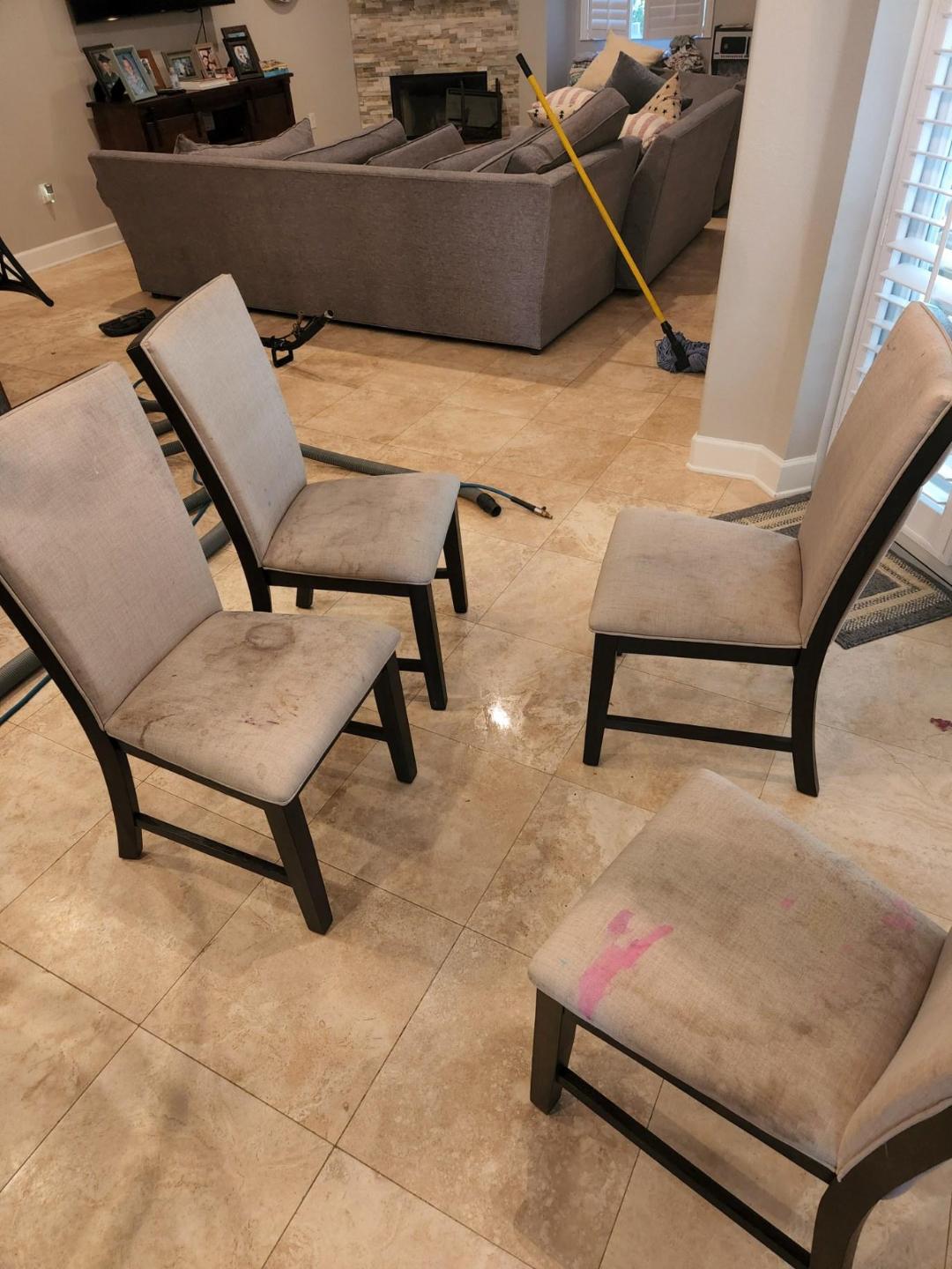 Four dining chairs with dirty seats on a tiled floor, in a living room.