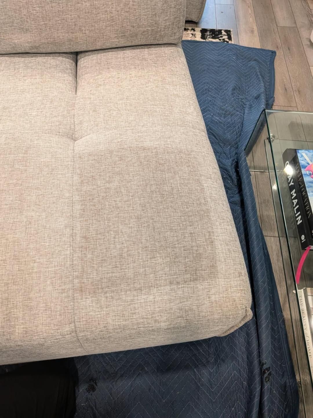 Light grey sofa with blue moving blankets.