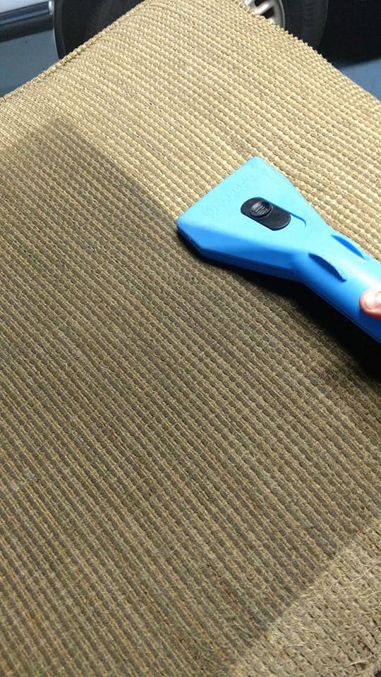 Cleaning upholstery with a blue handheld vacuum cleaner, showing the dirty versus clean fabric.