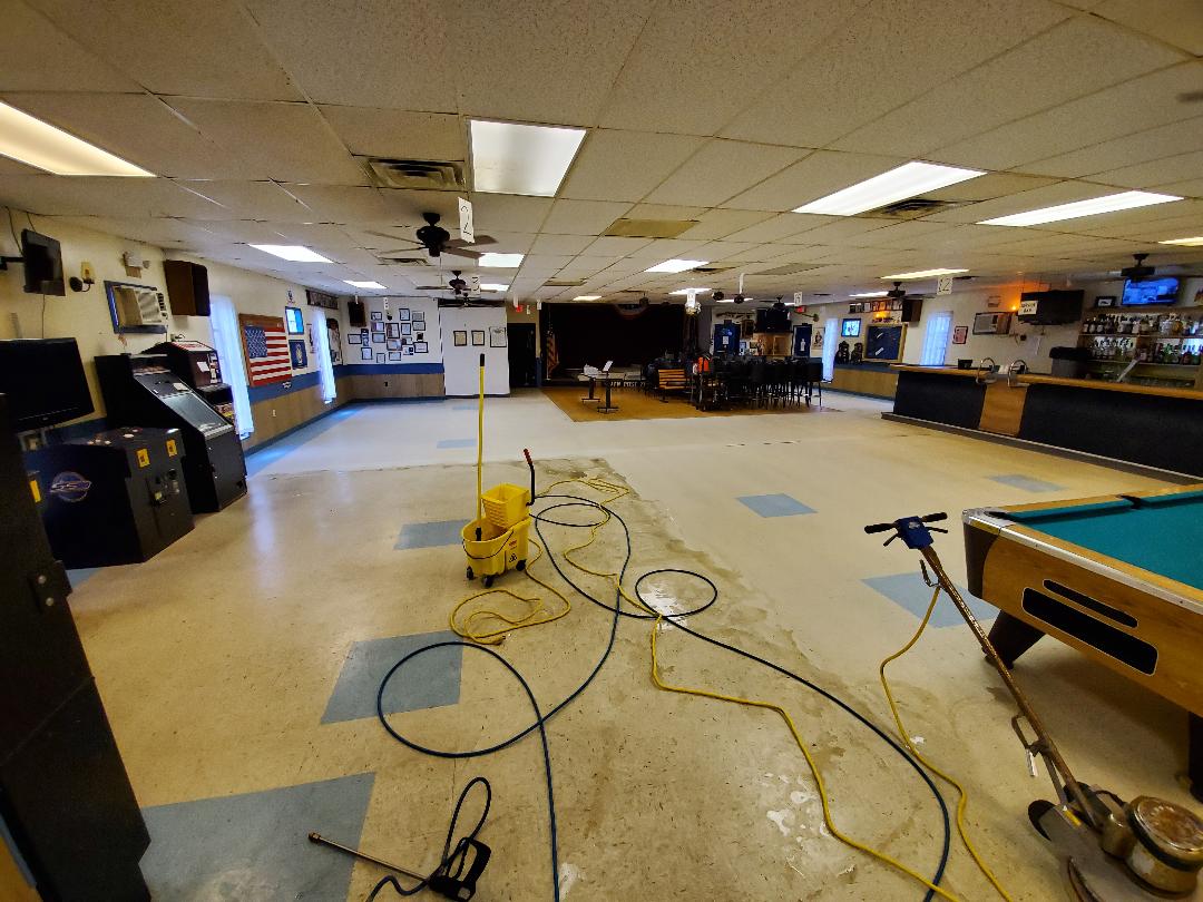 Interior of a bar being renovated; wet floor, cleaning equipment, pool table on the right.