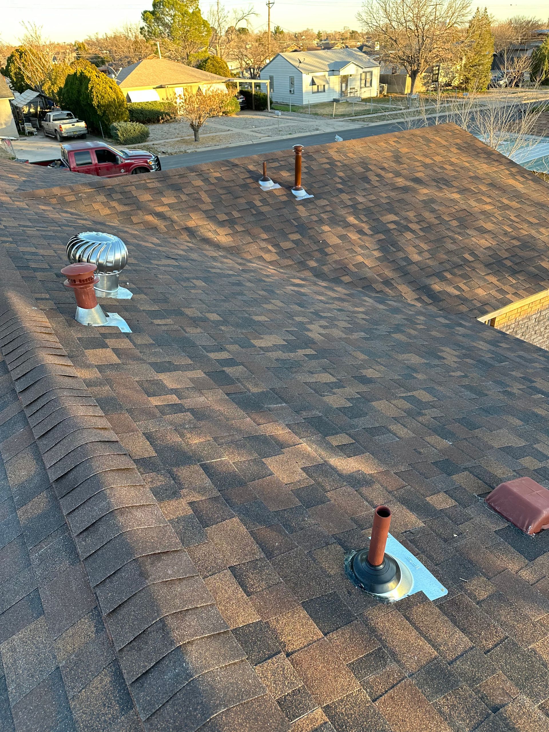 Clay roof tiles being installed, showing exposed wooden supports and underlayment.