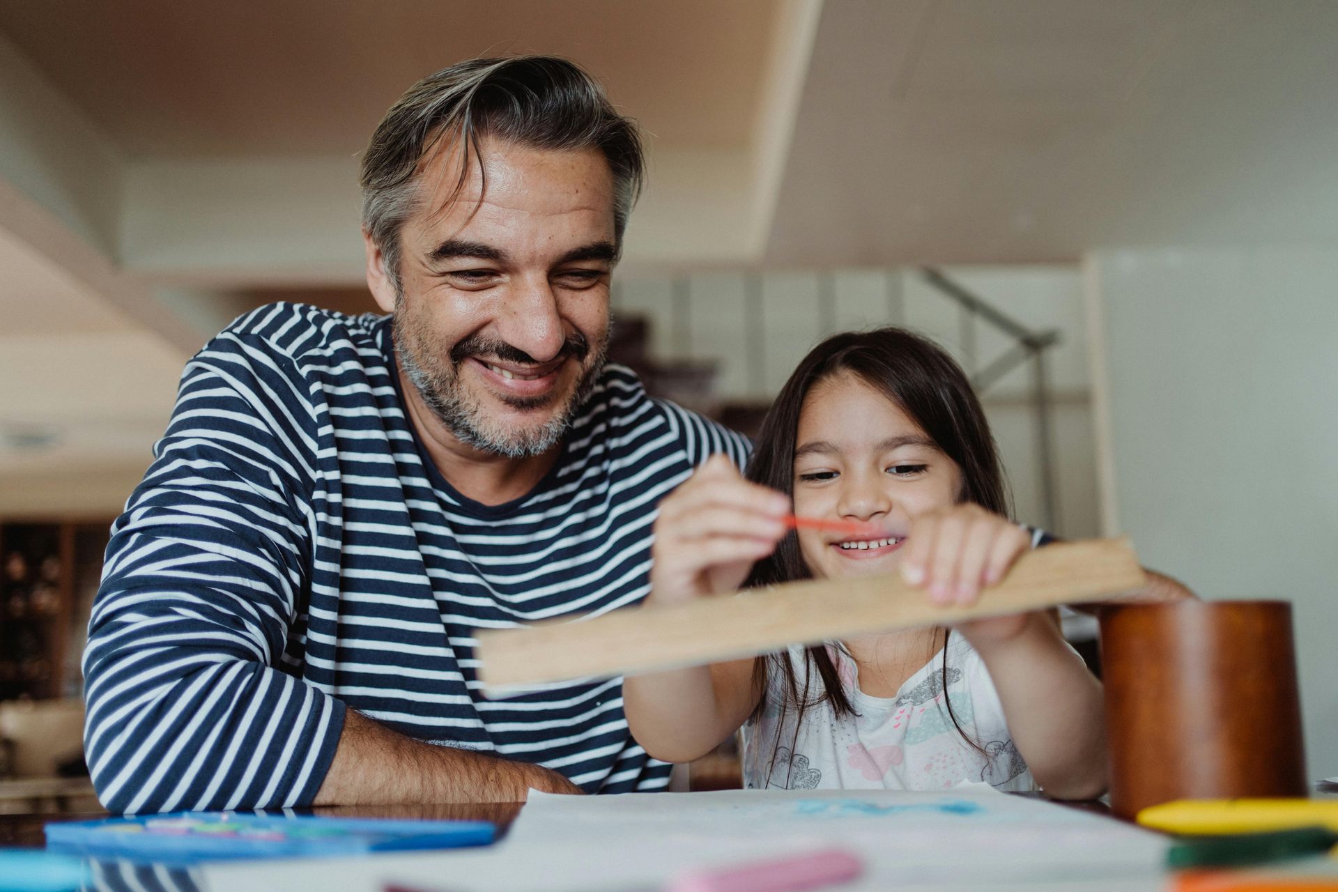A California homeschooling father and his daughter girl are sitting at a table working on math.
