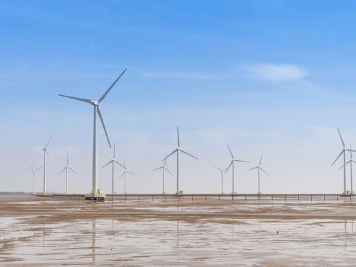 A row of wind turbines in a field with a blue sky in the background.