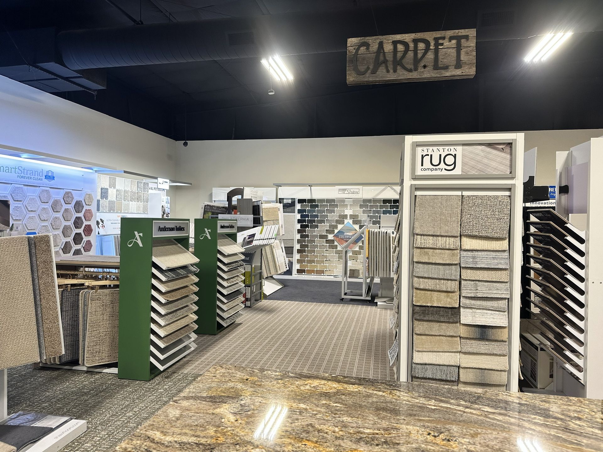 A showroom floor featuring rows of carpet sample displays and racks under a sign reading
