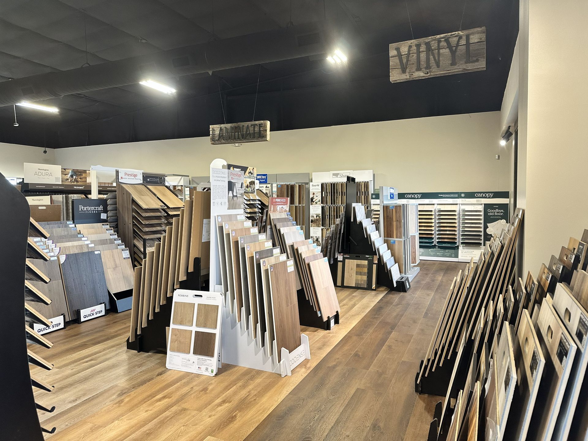 A showroom aisle featuring various flooring material samples on display racks under bright lighting.
