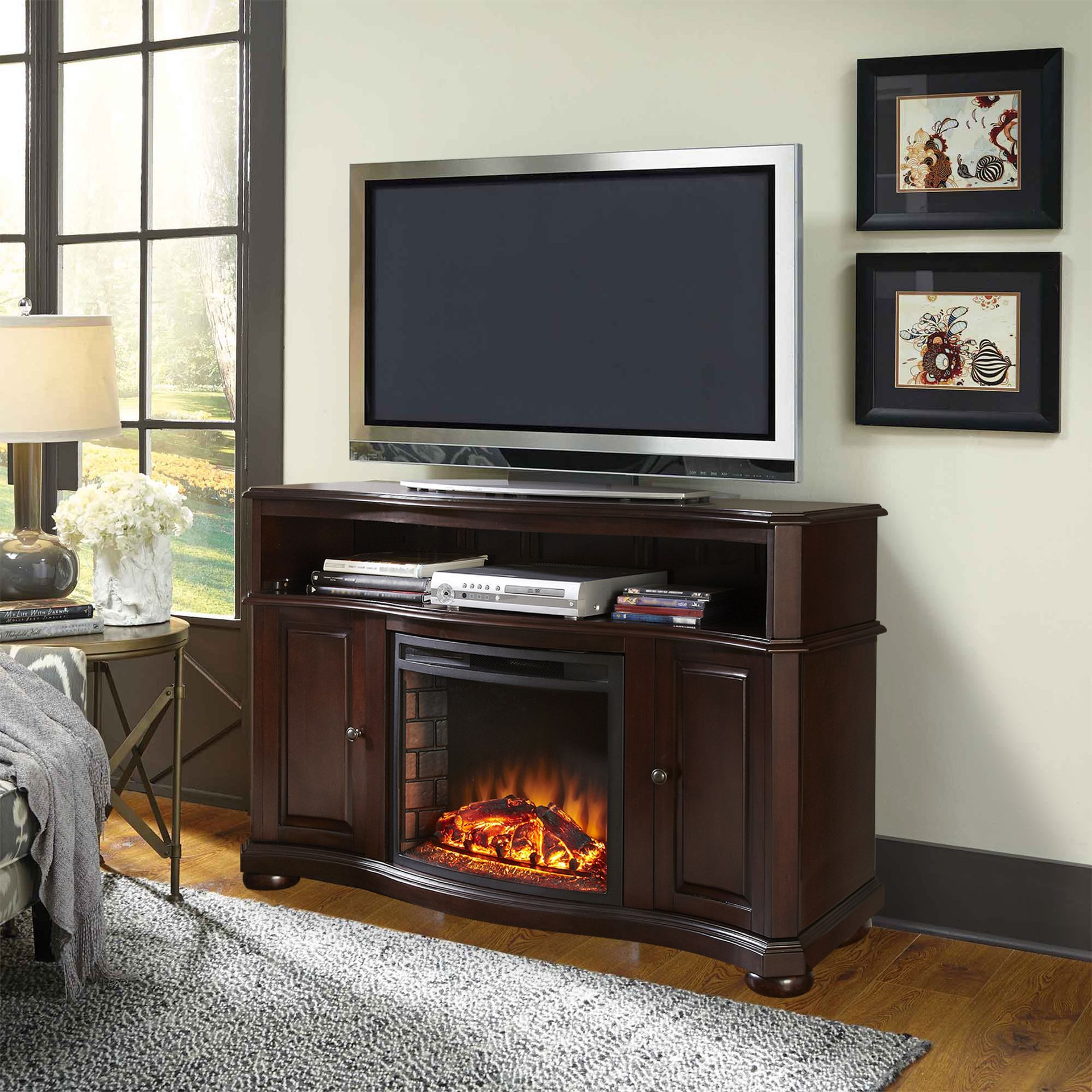 Dark brown TV stand with electric fireplace, TV, and framed artwork in a living room.