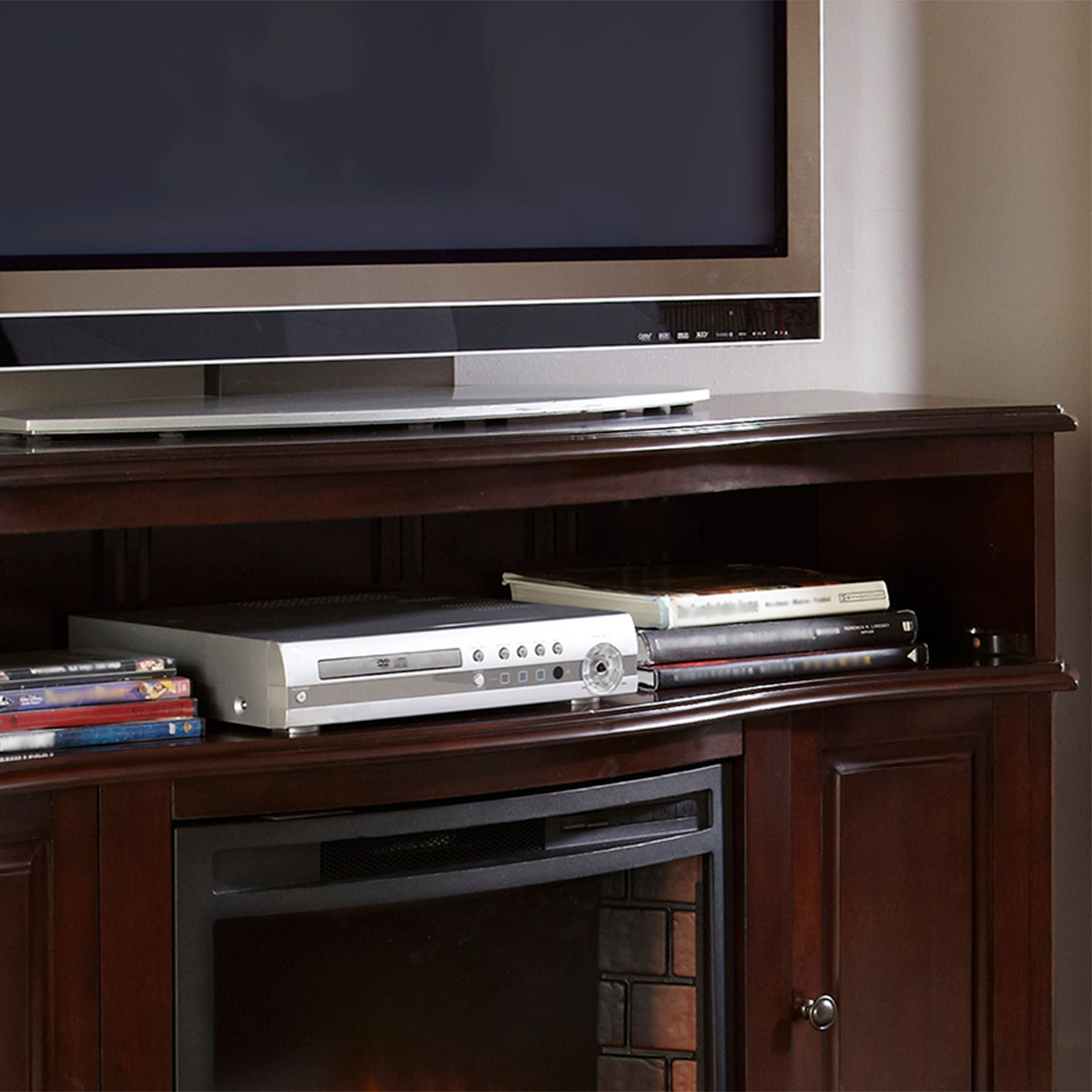 TV, DVD player, and DVDs on a dark wood entertainment center with an electric fireplace.