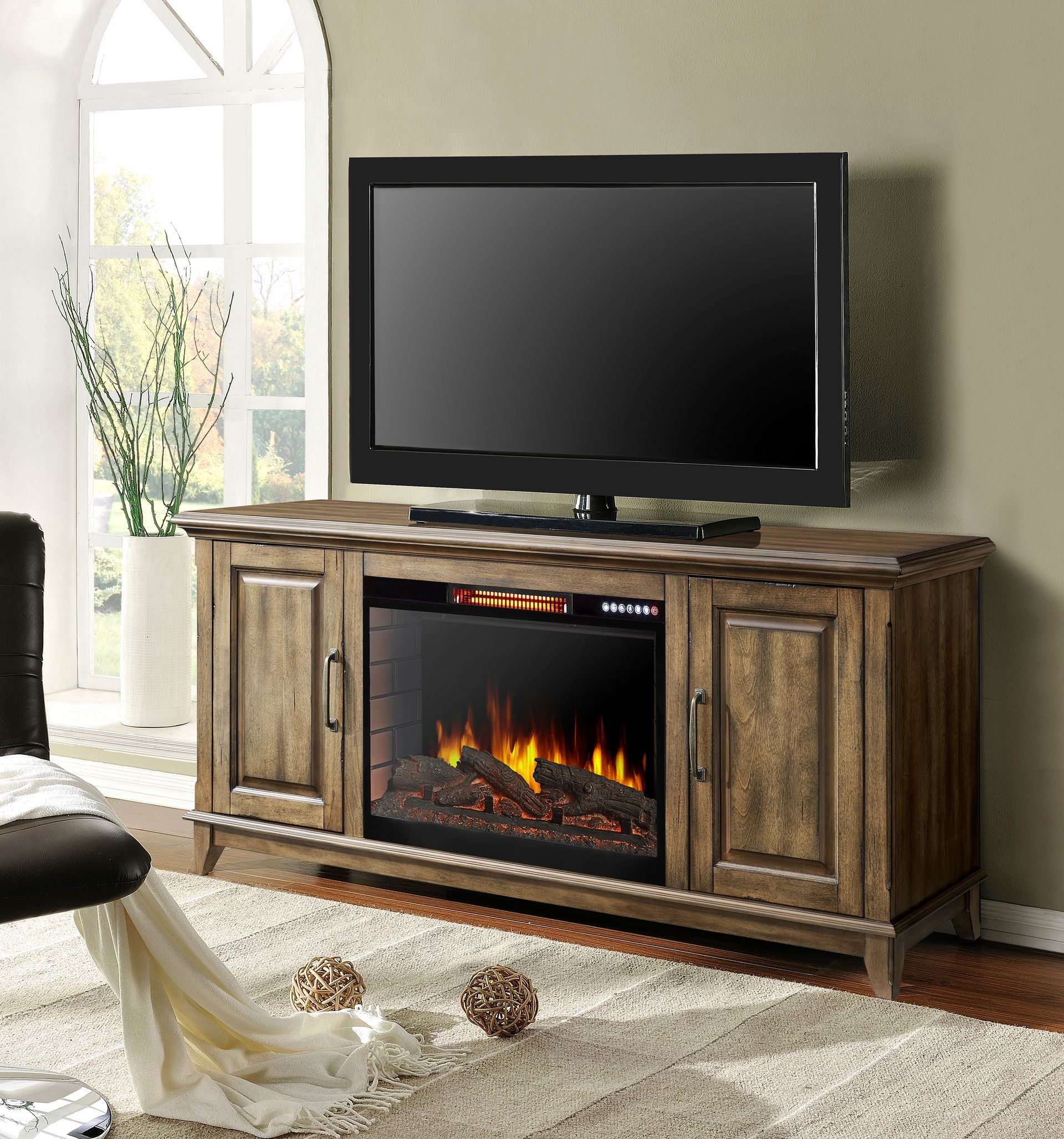 TV on a wooden media console with a built-in electric fireplace; set on a rug near a window.