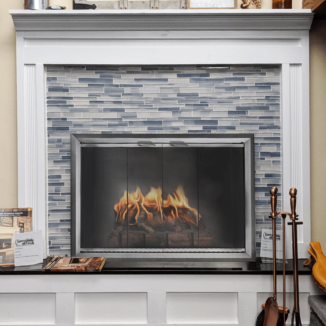 Fireplace with blue-tiled surround, lit fire, and white mantel. Black hearth with tools.