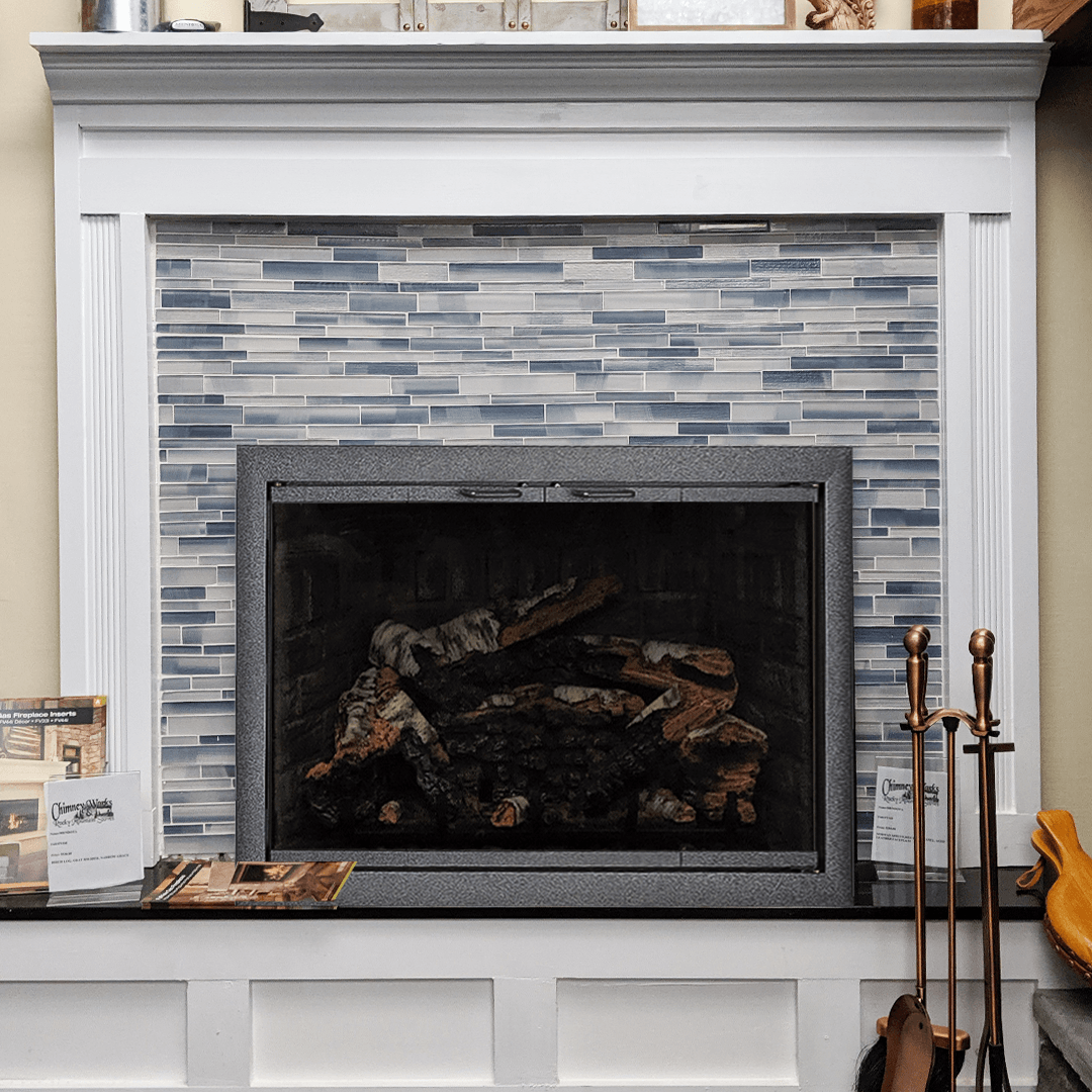 Fireplace with blue tiled surround, white mantel, and black hearth, with fire tools on the side.