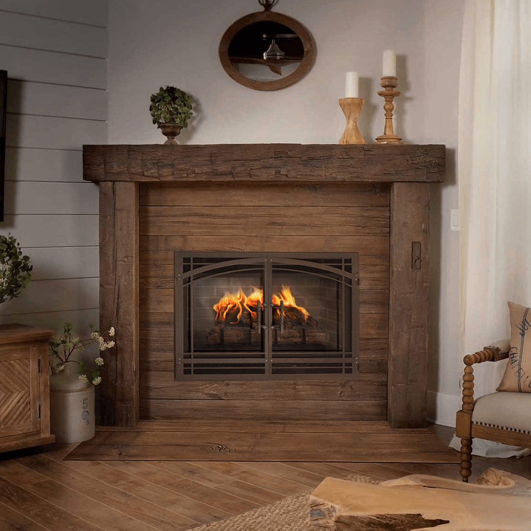 Rustic fireplace with burning flames, wooden mantel and surround, candles and greenery.