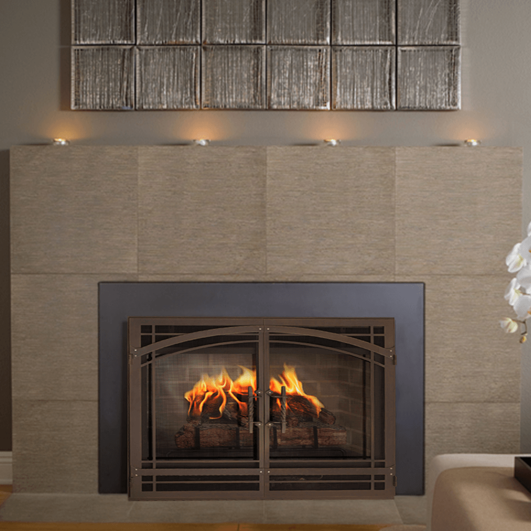 Fireplace with fire, brown metal screen, tan tiles, and wall sconces.