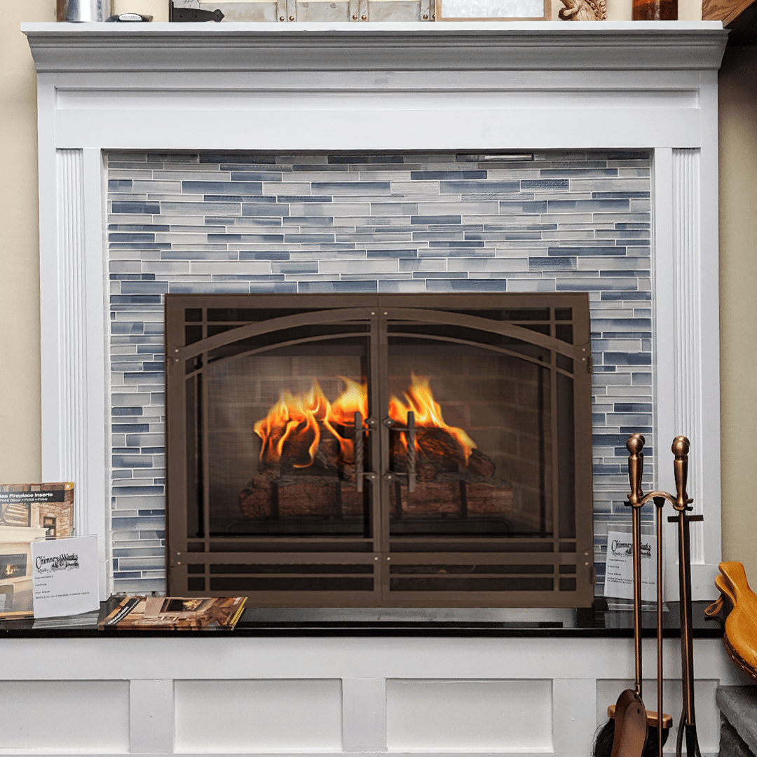 Fireplace with burning fire, brown screen, blue tile, and white mantel.
