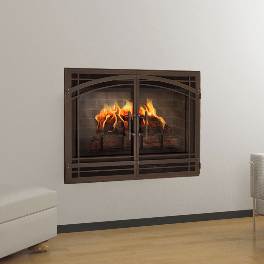 Fireplace with burning logs behind decorative brown metal doors, mounted on a white wall.