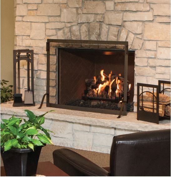 Fireplace with burning logs, stone surround, metal screen, and tools.