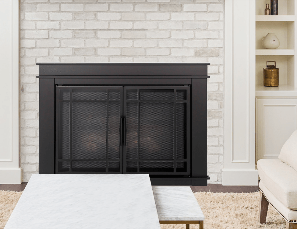Black fireplace with screen doors in front of a painted white brick wall. Marble table in front.