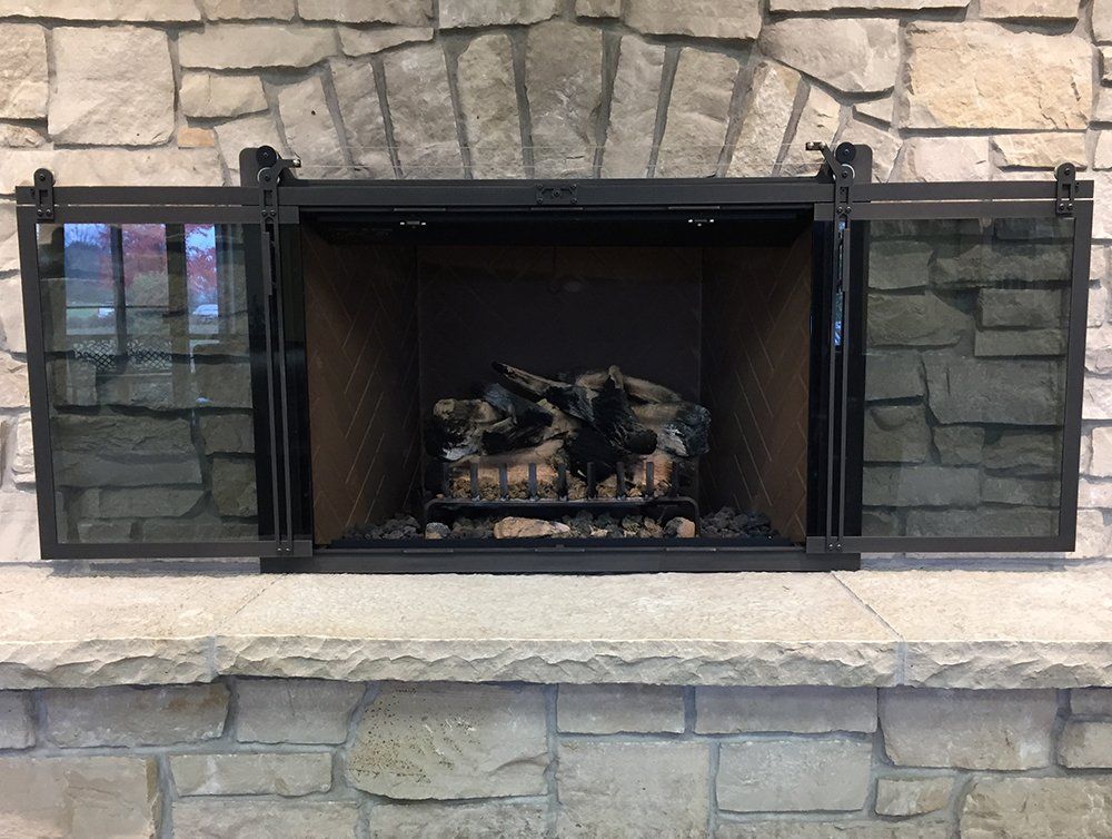 Fireplace with glass doors and stone surround.