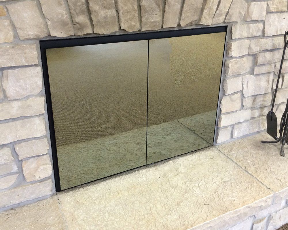 Fireplace with closed, reflective glass doors set in a stone surround.