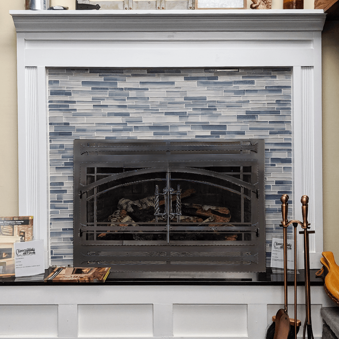 Fireplace with blue-tiled surround and black hearth. White mantel and trim. Black metal fire screen.