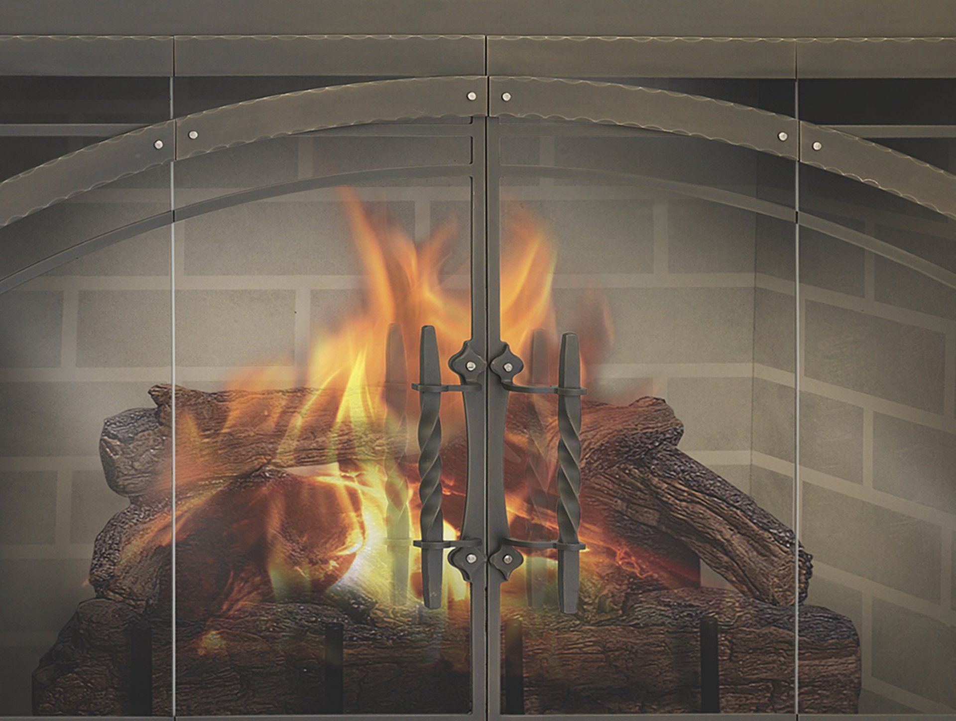 Fireplace with burning logs, behind glass doors and screen, brick background.