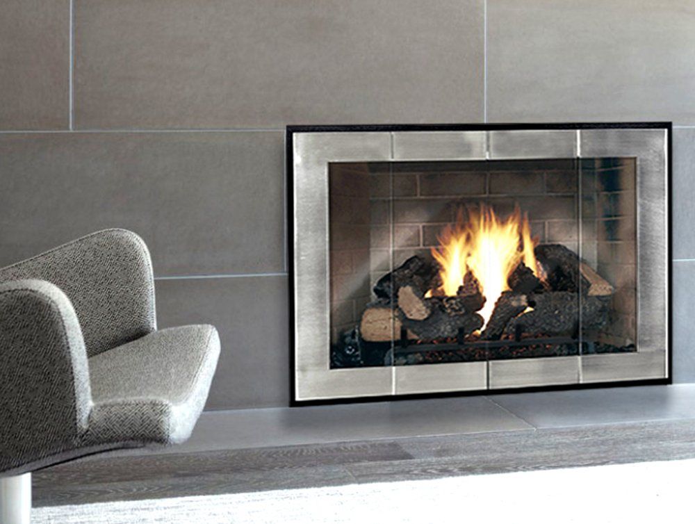 Fireplace with burning logs, mirrored frame, and armchair.