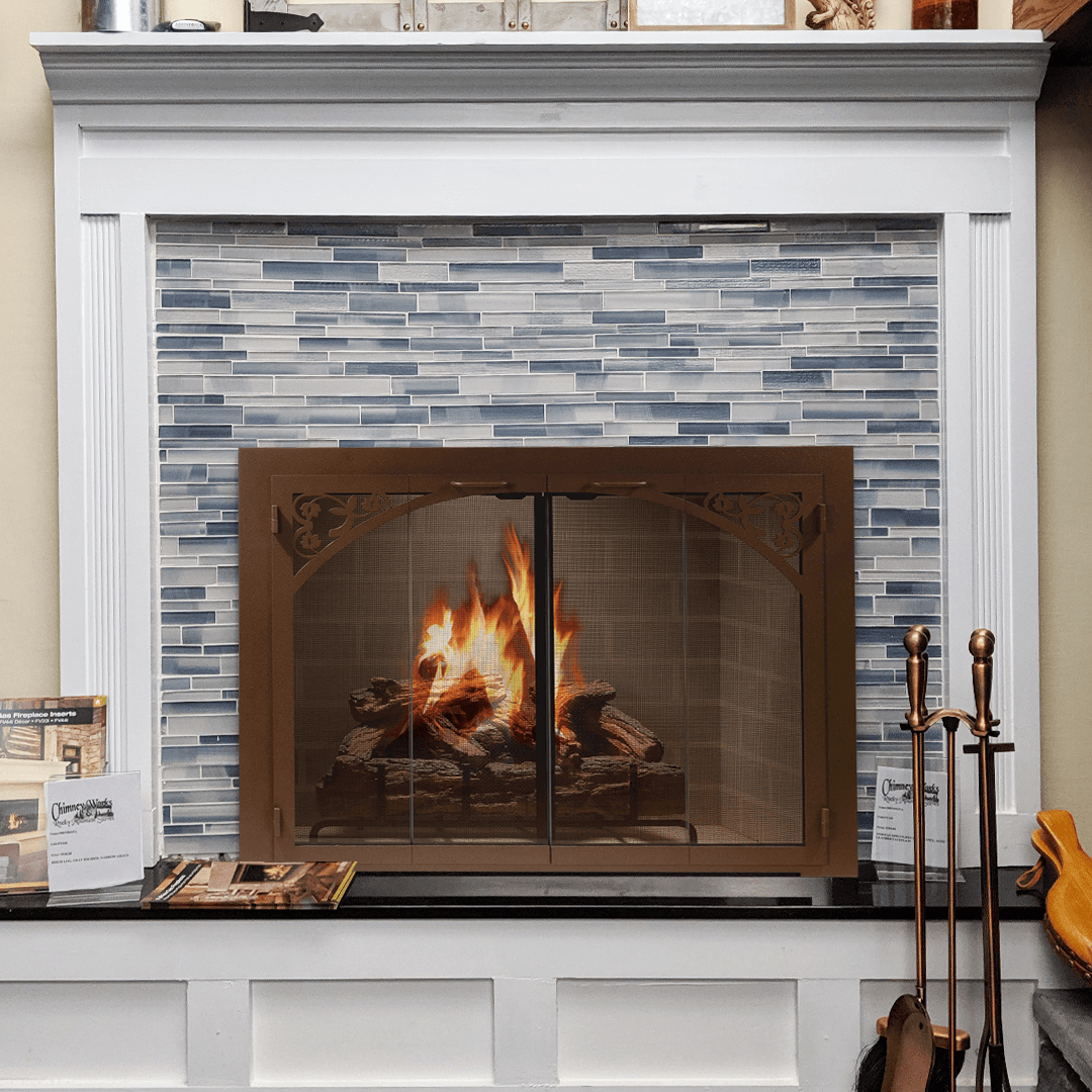 Fireplace with burning fire behind a decorative screen, blue tiled wall, and white mantel.