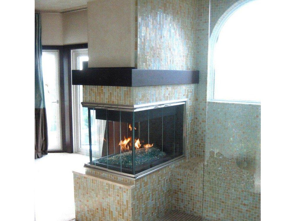 Modern fireplace with glass enclosure, flames visible, set in a tiled wall, dark wood trim.