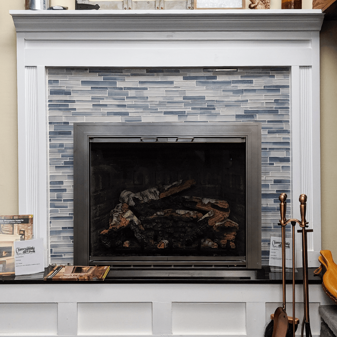 Fireplace with blue tile backsplash and white mantel. Black hearth and metal firebox.