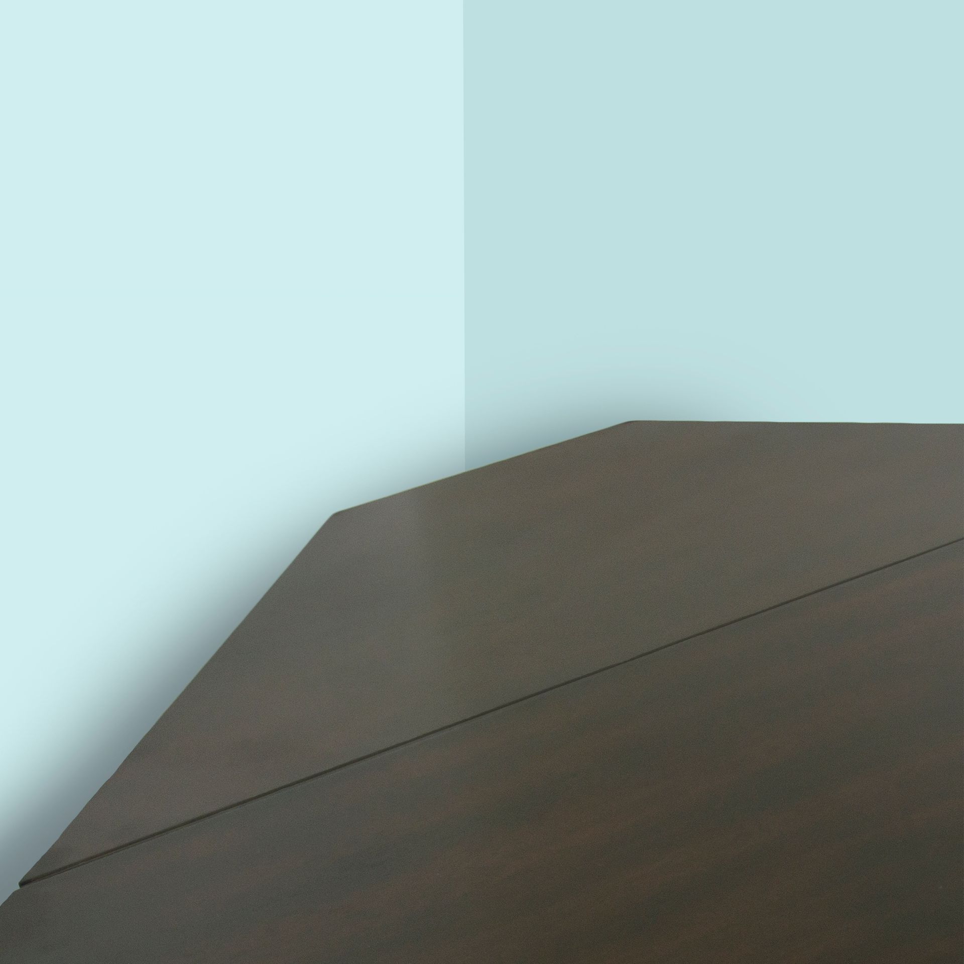 Dark brown desk in a corner against a light blue wall.