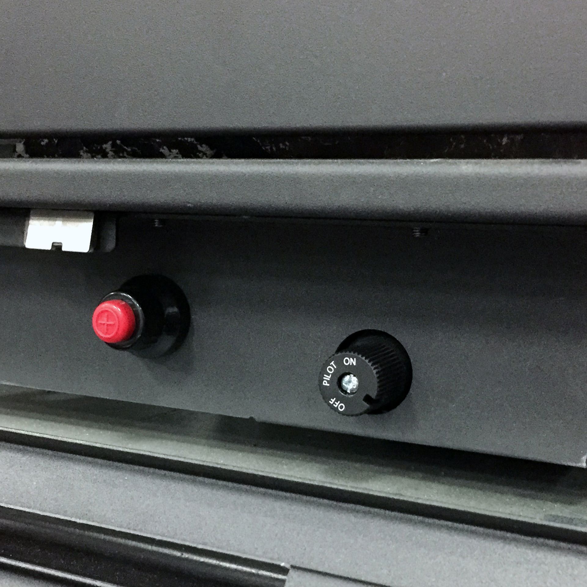 Two black knobs on a dark surface; one is red and one is black with