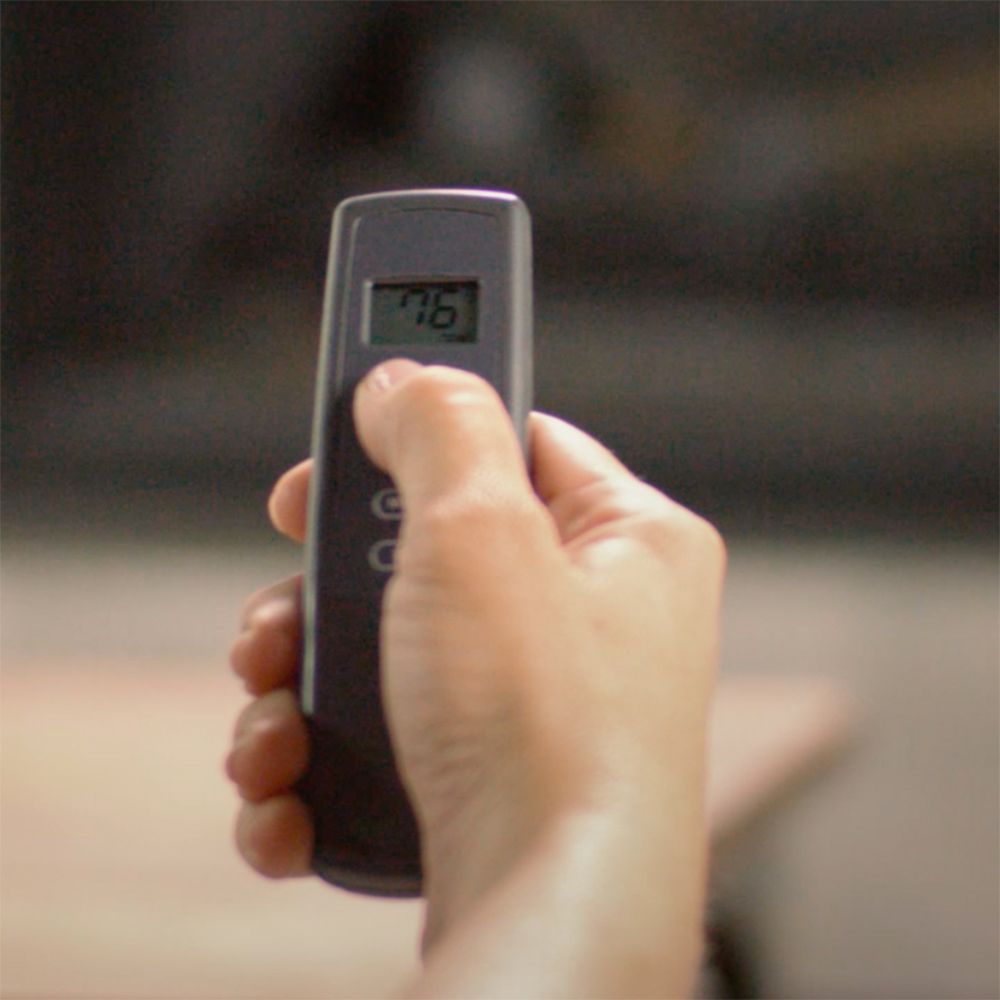 Hand holding a gray remote with a display showing