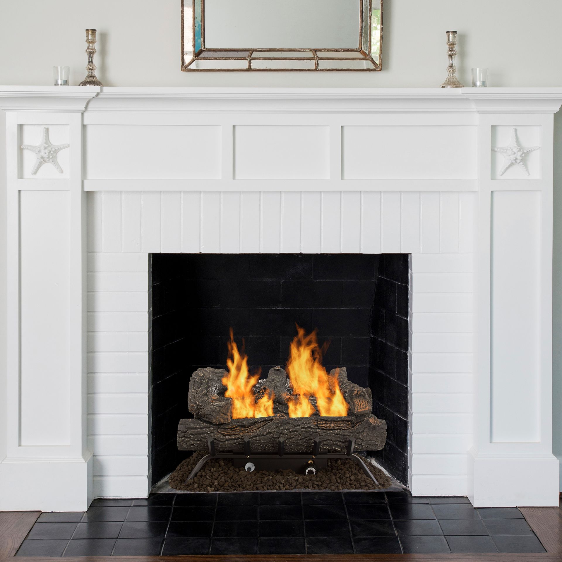 White fireplace with burning gas logs, black tile interior, and decorative mirror above.