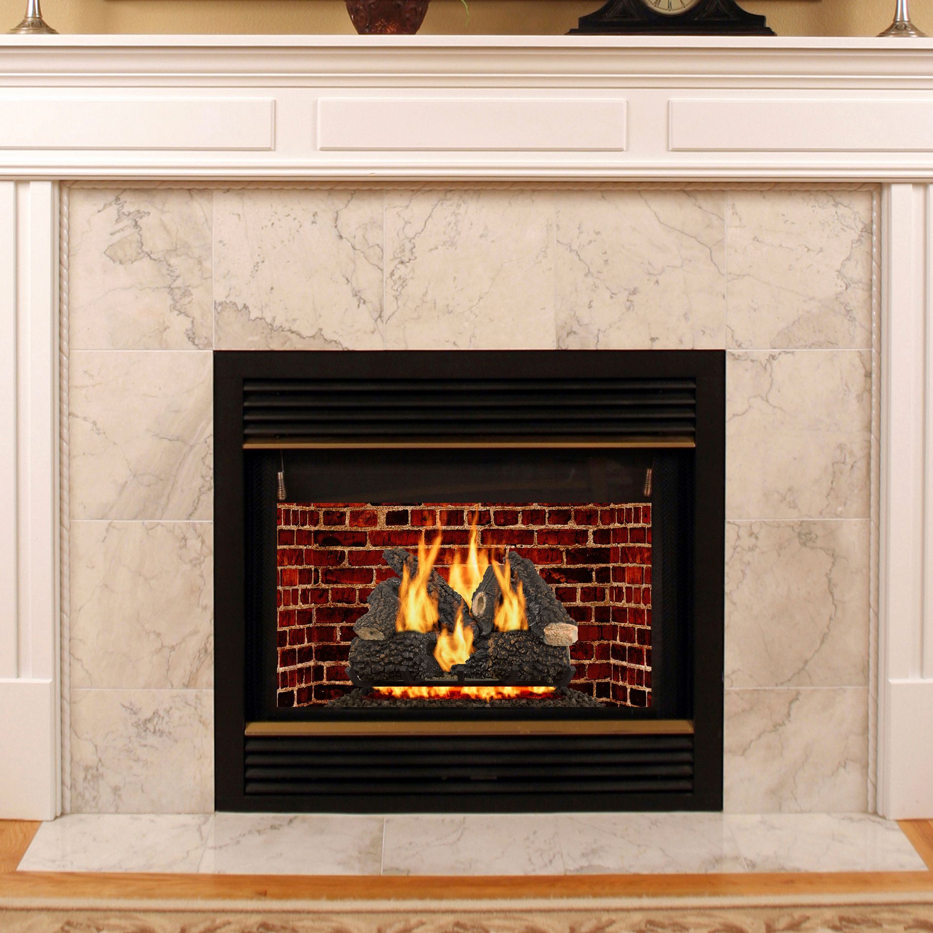 Fireplace with flames and faux logs, set in a brick-lined hearth, surrounded by white marble tile and wooden mantel.