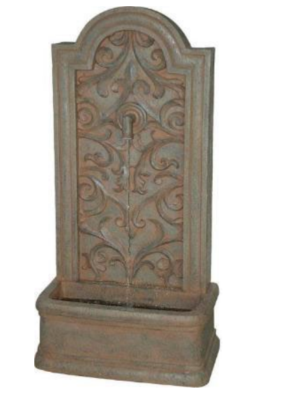 Stone wall fountain with ornate scrollwork design and basin.