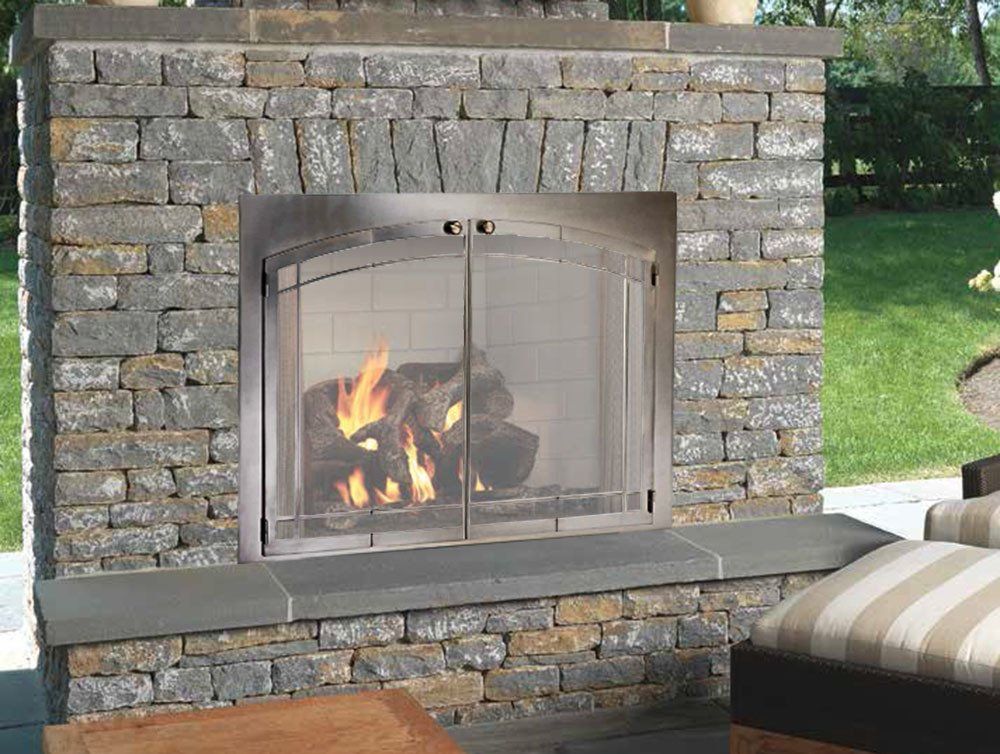 Stone fireplace with a burning fire, glass doors, and seating nearby.