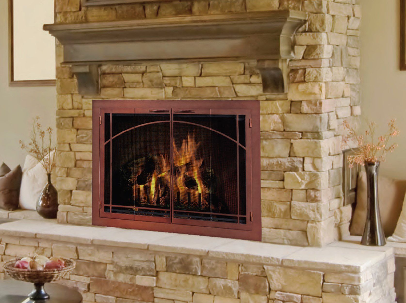 Fireplace with stone surround, lit flames, and glass doors.
