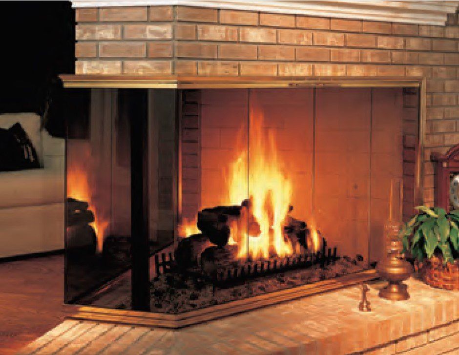 Fireplace with a burning fire behind glass doors, brick and wooden trim.