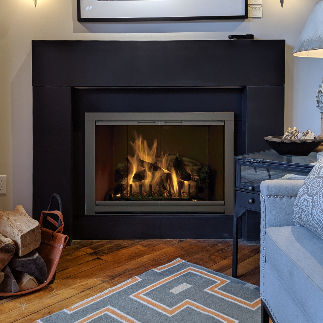 Fireplace with burning logs, dark surround, wooden floor, and blue patterned rug.