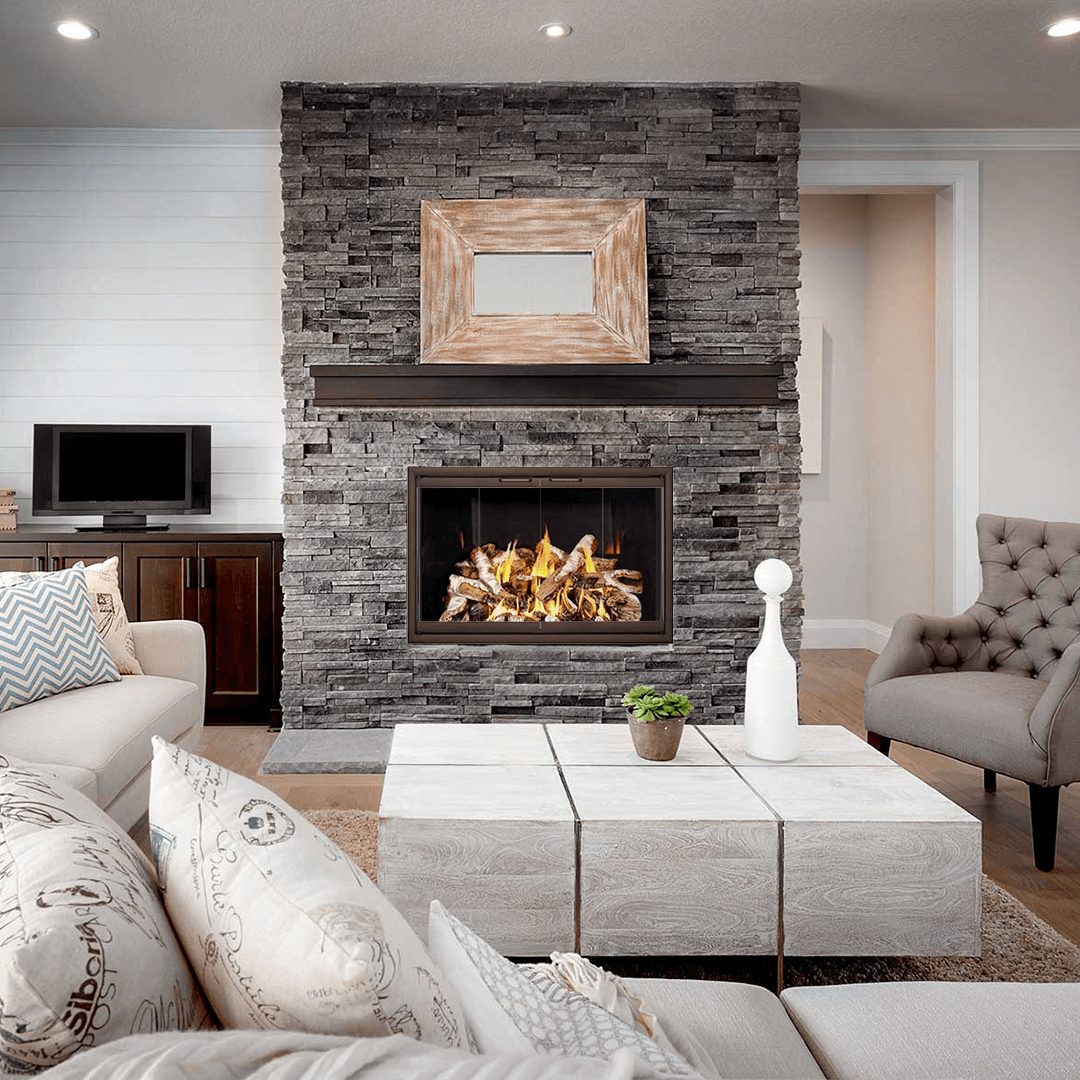 Living room with stone fireplace, lit fire, and neutral-toned furniture.