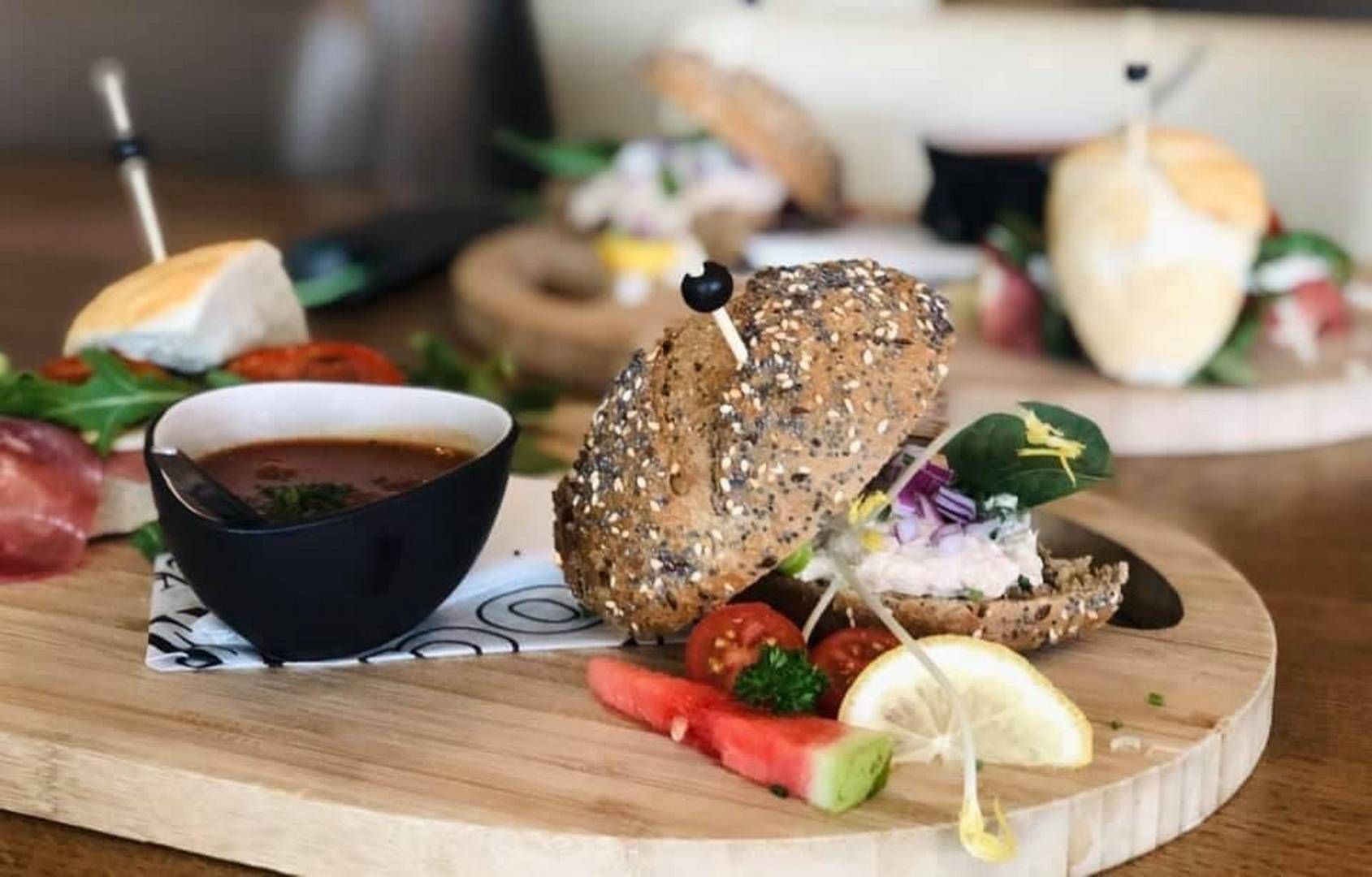 Een close-up van twee sandwiches met gerookte zalm en eisalade op gesneden volkorenbrood met verse rucola.
