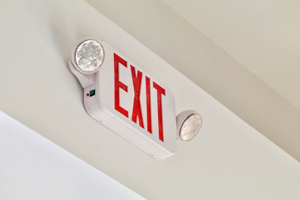 A Red Exit Sign is Hanging From the Ceiling of a Building — Mick Sawtell Electrical Pty Ltd in South Lismore, NSW