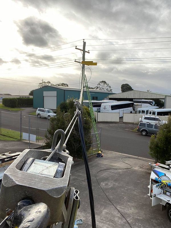 A Ladder is Attached to a Power Line in a Parking Lot — Mick Sawtell Electrical Pty Ltd in Robina, QLD