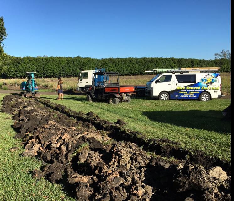A Van is Parked in a Grassy Field Next to a Tractor — Mick Sawtell Electrical Pty Ltd in Kyogle, NSW
