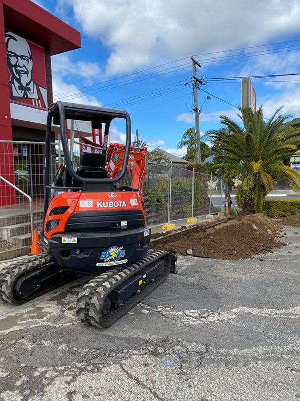 A Small Excavator is Parked in a Parking Lot — Mick Sawtell Electrical Pty Ltd in Casino, NSW