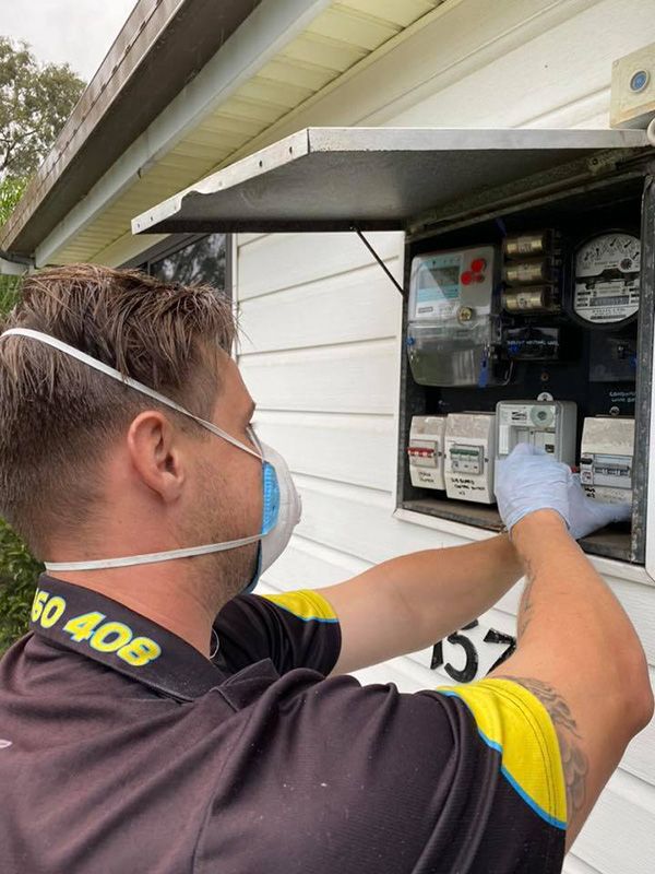 A Man Wearing a Mask and Gloves is Working on an Electrical Box — Mick Sawtell Electrical Pty Ltd in South Lismore, NSW