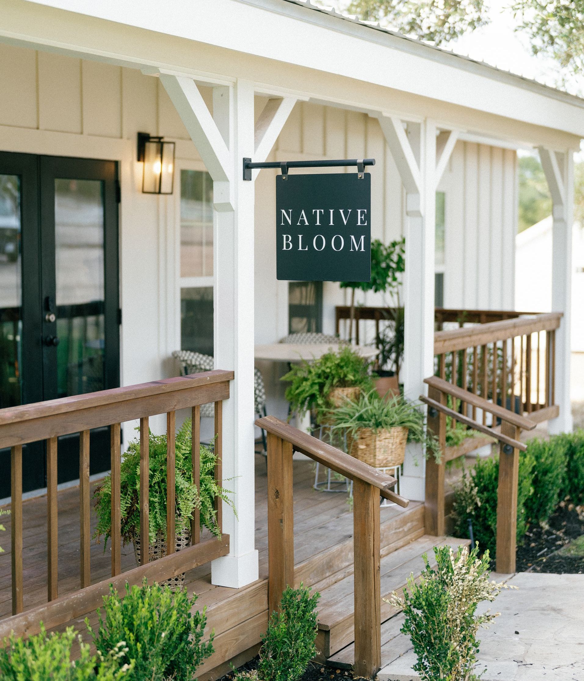 Covered entrance with white posts, wooden ramp, and green 